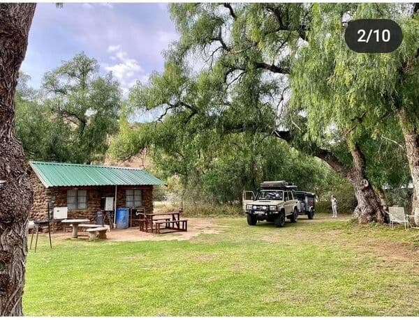 Stone building with 4x4 vehicle and shade trees
