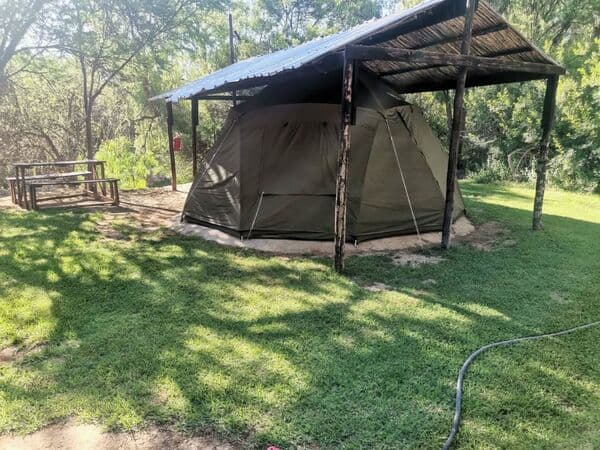 Canvas tent under wooden shelter with picnic area