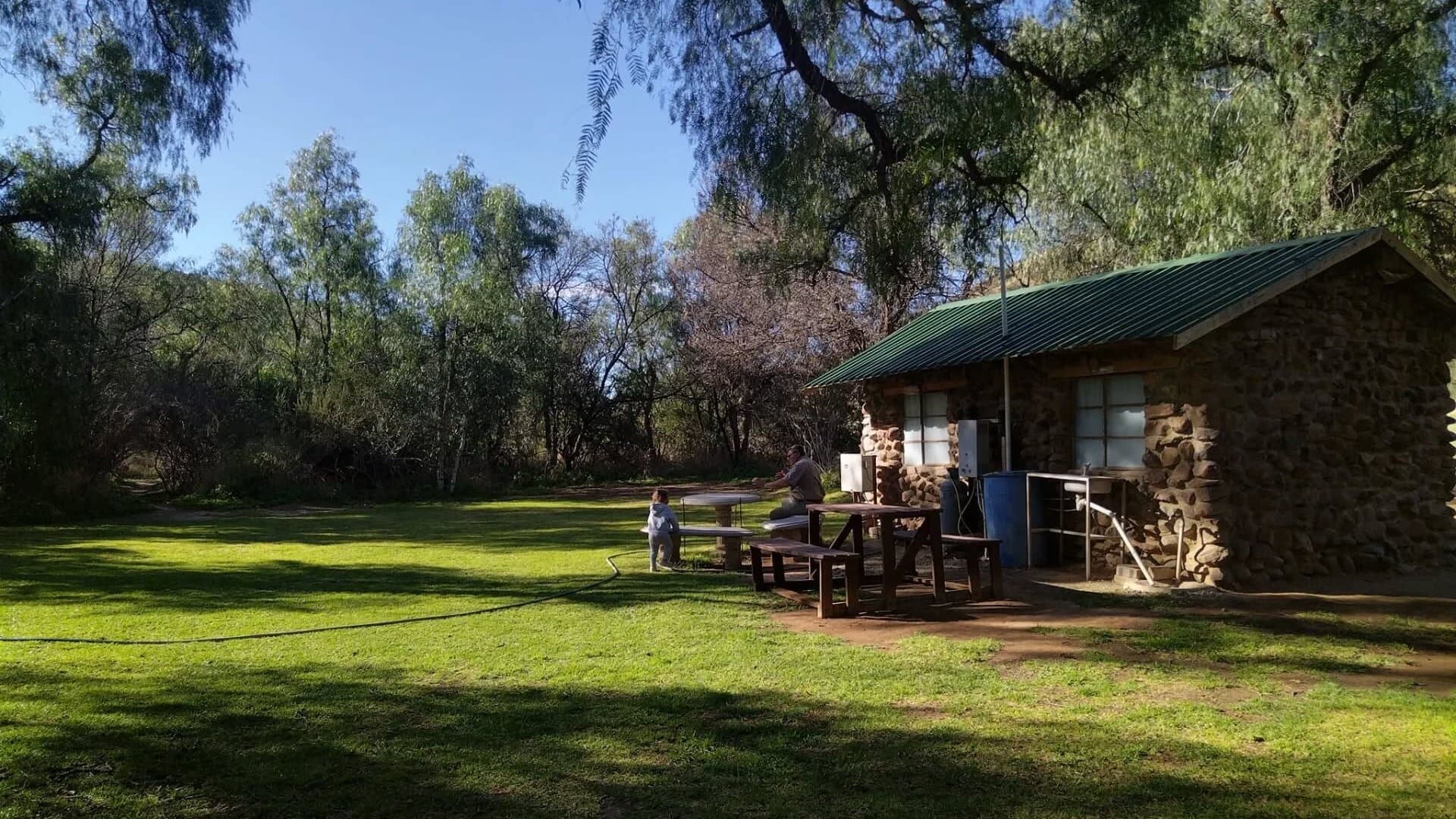 Stone building and green grounds at Red Dune Camp